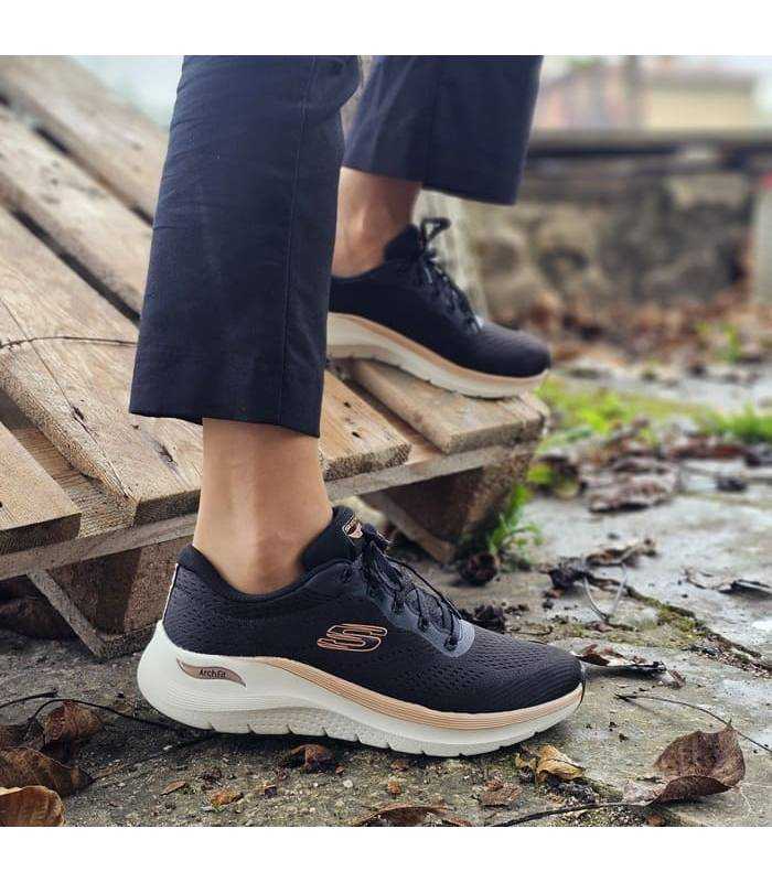 Mujer posando con las zapatillas deportivas negras arch fit de Skechers