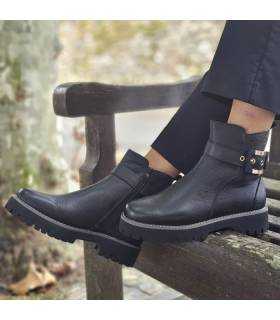 botines de mujer en piel negra con cremallera puestos posando sobre un banco