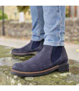 hombre posando sobre un banco de piedra con los botines Chelsea de piel azules puestos