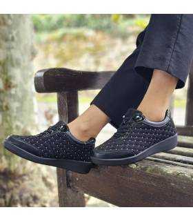 Zapatos deportivos mujer Doctor Cutillas negros con bolitas plateadas puestos en banco de madera