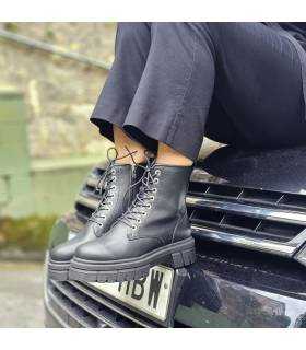 mujer posando encima de un coche con las botas de piel negras tipo militar puestas