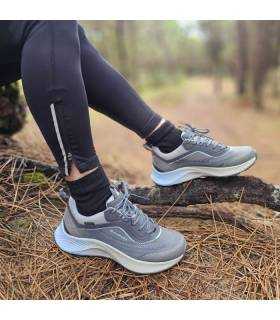 mujer posando sentada en un pinar con las zapatillas de senderismo con gortex de Chiruca azules