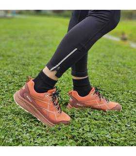 modelo posando en el campo con las zapatillas de trekking naranjas de nicocboco puestas