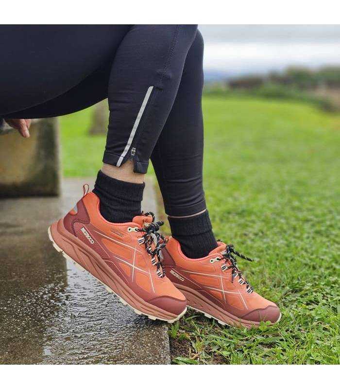 mujer sentada con las zapatillas de trekking puestas naranjas de Nicocboco