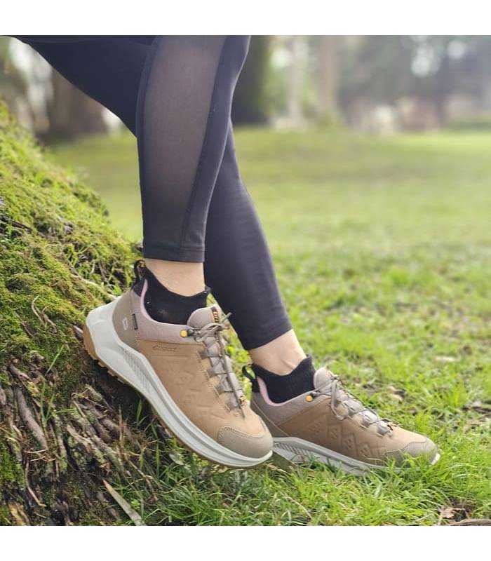 mujer posando sobre un tronco con las zapatillas de senderismo comodas e impermeables de Grsiport