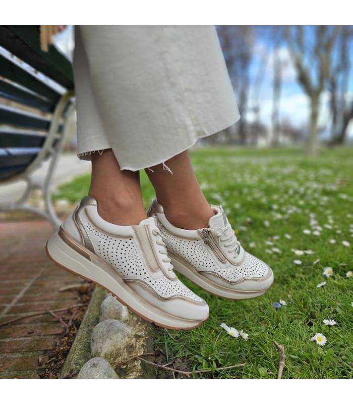 pies cruzados con los zapatos deportivos de piel beige fabricados por Treintas puestos