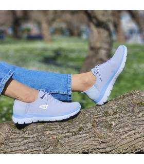 mujer posando en el campo con las zapatillas azules de Skechers slip-ins puestas