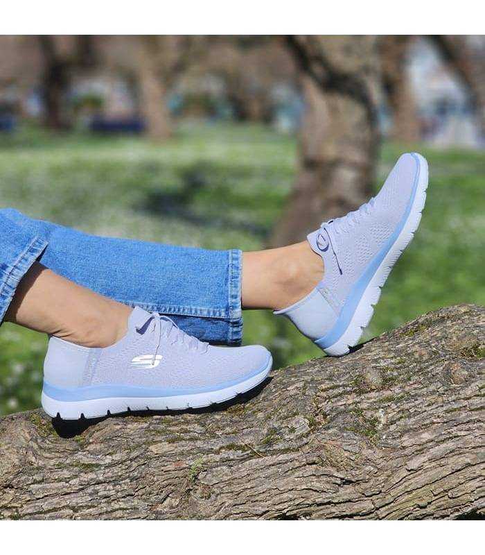 mujer posando en el campo con las zapatillas azules de Skechers slip-ins puestas
