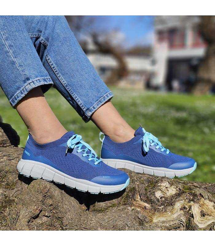 mujer posando sobre un tronco con las zapatillas deportivas Criptana azules puestas