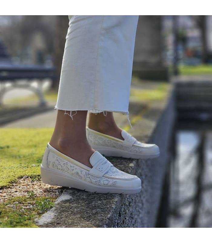 mujer posando junto al estanque con los zapatos comodos de cuña balncos puestos