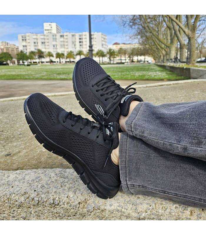 hombre posando con las zapatillas negras de Skechers Track Leshur puestas
