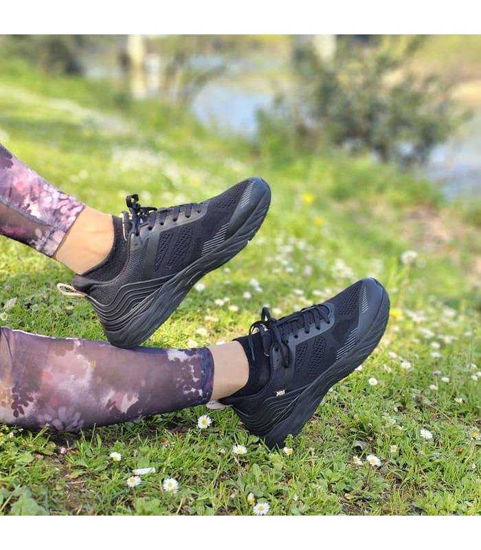 mujer posando en el campo con las zapatillas deortivas negras de xti puestas