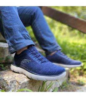 hombre posando con vaqueros y las zapatillas deportivas azules comdas de Skechers puestas